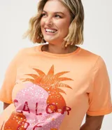 Remera color durazno de algodón con cuello redondo y mangas cortas. Presenta un estampado de piña con detalles de lentejuelas y la frase "Calor de Verão".