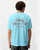 Remera blanca de algodón con cuello redondo y estampado en la espalda con la frase "Malibu Sports Club by Rona Studio" en color rojo.