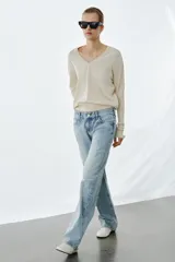 Jeans de tiro bajo, corte recto y largo completo, con efecto lavado y detalles de rotos en el delantero. Cierre frontal con cremallera y botón, y diseño de cinco bolsillos.