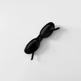 Lentes de sol negros con forma ovalada y marco grueso.