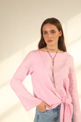 Blusa rosa de lino con corte asimétrico y lazo en la cintura.