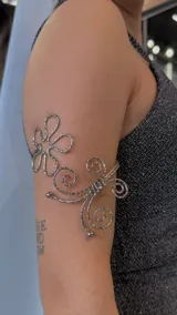 Brazalete plateado con diseño de flor y espirales.