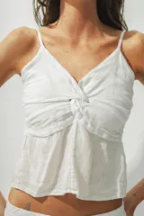 Top blanco con breteles finos y detalle de nudo en el centro del busto.