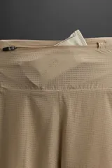 Shorts deportivos color marrón confeccionados en tejido técnico ligero y elástico. Cuenta con cintura elástica ajustable con cordón interior, bolsillos frontales, bolsillo trasero con cierre de cremallera, forro interior y bajo con aberturas laterales.