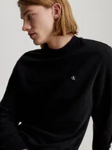 Buzo negro de felpa de algodón y poliéster, con cuello redondo, mangas largas, puños y dobladillo acanalados. Presenta el logo de Calvin Klein bordado en el pecho.