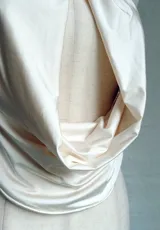 Top color crema o amarillo pálido, estilo halter con cuello atado y escote pronunciado en V con drapeado frontal. El cuello está adornado con una flor de orquídea en tonos amarillo, naranja y rosa.