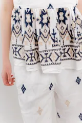 Blusa blanca de algodón con bordados artesanales en verde y corte suelto.