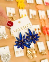 Par de aros colgantes con forma de flor, compuestos por múltiples pétalos de cristal facetado de color azul cobalto, engarzados sobre una base metálica dorada. El centro de la flor es una cuenta redonda del mismo color.