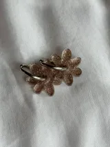 Aros colgantes plateados con dije de flor acrílica color dorado.