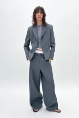 Blazer azul con cuello solapa y manga larga. Tiene un bolsillo de vivo en el pecho y cierre frontal con botones ocultos.