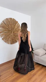 Vestido largo negro de tejido de punto con escote recto y breteles finos. La falda es de encaje transparente. Incluye una bufanda fina al tono.