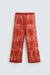 Pantalón relaxed fit de punto ligero tejido en hilatura de algodón color ladrillo con estampado a cuadros difuminados en blanco. Cintura elástica ajustable con cordón y bolsillos laterales.