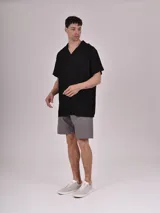 Camisa de manga corta con estampado de hojas color verde sobre fondo beige, cuello solapa y bolsillo en el pecho.