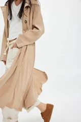 Tapado largo de tejido de punto color beige con diseño a cuadros sutil. Presenta cuello solapa, cierre frontal con botones y bolsillos laterales.