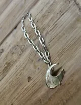Collar plateado con cadena de eslabones grandes y dije de luna creciente texturizada. El dije está hecho de alpaca y bronce.