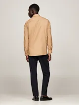 Camisa color beige de corte regular, confeccionada en algodón elástico. Cuenta con cuello abotonado, mangas largas con puños abotonados y logo de Tommy Hilfiger bordado en el pecho.