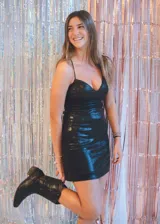 Vestido corto color fucsia con textura brillante, breteles finos y escote recto. Presenta corte tipo corsé con costuras fruncidas y falda ajustada.