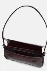 Bolso de hombro color crema con efecto acharolado, solapa con cierre imantado y asa ajustable.
