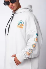 Buzo canguro gris claro de corte oversize, con capucha y cordones negros con letras blancas. Presenta un bolsillo tipo canguro y un estampado pequeño en el pecho y otro en la manga.