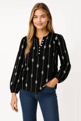 Blusa color crema con estampado de hojas color marrón, cuello mao con abertura y botones, mangas largas abullonadas con puños elásticos.