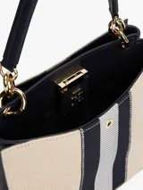 Cartera tote de lona color beige con rayas verticales azul marino y blanco. Tiene asa superior, correa ajustable y extraíble, cierre magnético y múltiples compartimentos interiores.