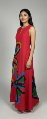Vestido largo rojo de lino liviano, con silueta amplia y fluida, escote con pequeña abertura frontal, bolsillos laterales y estampado de flores abstractas en tonos verde, azul y negro. Diseño exclusivo de la marca con tintas ecológicas. Hecho en Uruguay.