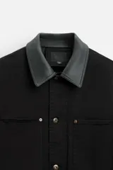 Parka negra de algodón con cuello solapa de cuero sintético, corte recto, acolchada y con cierre frontal de botones.