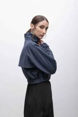 Campera cropped de inspiración deportiva, color azul marino, con cuello alto, cierre frontal a tono, bolsillos funcionales y puños elastizados. Confeccionada en tela campera repelente al agua, con interior de micropolar.
