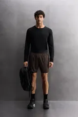 Shorts deportivos color beige con cintura elástica negra, bolsillos laterales y logo estampado en la pierna.