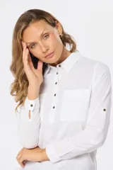 Camisa blanca de lino con mangas largas, cuello clásico, medio abotonada y bolsillo en el pecho. Tiene presilla en la manga para mayor comodidad.