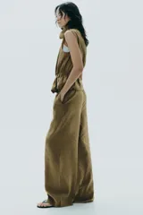 Pantalón palazzo color verde oliva de tejido fluido, tiro medio, cintura elástica ajustable con cordones y bolsillos laterales.