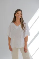 Blusa blanca de lino con escote en V, mangas cortas amplias y estampado floral en relieve.