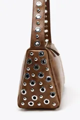 Bolso de hombro marrón con apliques metálicos plateados en los laterales y en la correa. Cierre con cremallera.