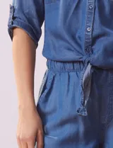 Blusa celeste de tencel, marca Alex & Parker. Cuello a la base, escote en V y abertura central con botones. Delantera con bolsillos. Largo de manga regulable con presilla y botón. Terminación de ruedo con nudo.