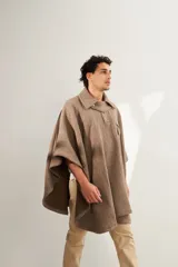 Poncho unisex de lana fina color marrón claro, con cuello polo, cartera con broches a presión y bolsillo ojal.