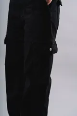 Pantalón cargo negro de pana, corte ancho, con bolsillos laterales y traseros con solapa.