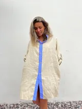 Vestido camisero beige de lino con cuello y solapa azul lavanda, cierre frontal con botones y mangas largas.