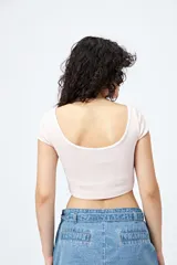 Top corto de punto acanalado color rosa, con silueta ajustada, escote redondo y ribetes blancos en cuello y mangas.