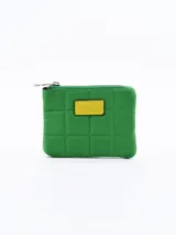 Monedero cuadrado verde acolchado con cierre superior y parche rectangular amarillo en el centro.