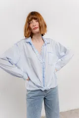 Camisa color crema de manga larga con cuello camisero y detalles de encaje en el escote. Se ata en la parte delantera.