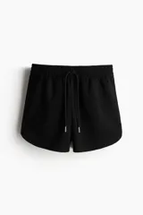 Short negro de felpa liviana de mezcla de algodón, con elástico revestido en la cintura, cordón para ajustar y bolsillos discretos en las costuras laterales.