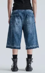 Bermuda larga de denim con calce oversize, desgaste y ruedo desflecado.