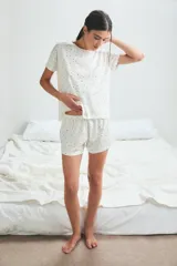 Conjunto de pijama blanco con estampado de lunares negros, compuesto por una remera de mangas cortas y un short con cintura elástica.