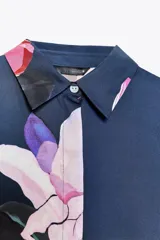 Camisa azul con estampado de flores rosas, cuello solapa y manga corta.
