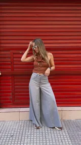 Pantalón de jean celeste de tiro medio con pierna extra ancha y caída fluida, con bolsillos delanteros y traseros, y cierre frontal con cremallera y botón metálico.