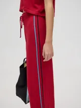 Pantalón negro de algodón, corte holgado y pierna ancha con pretina elástica. Presenta rayas blancas y celestes a los costados.