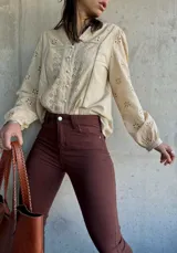 Camisa color manteca con bordado inglés, cuello en V y mangas largas abullonadas.