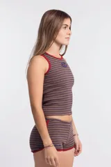 Musculosa ajustada de tejido acanalado, color marrón con rayas finas horizontales en azul oscuro. Presenta ribetes en color rojo en el cuello y las sisas. Lleva un pequeño logo bordado en el pecho.
