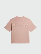 Remera de algodón color rosa pálido, con cuello redondo y manga corta. Presenta un dobladillo deshilachado en el cuello y en los bordes de las mangas.