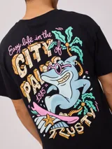 Remera color crema de algodón con estampado en la espalda de un tiburón con gafas de sol, palmeras y texto "Easy life in the City of Palm Rusty 1985".
